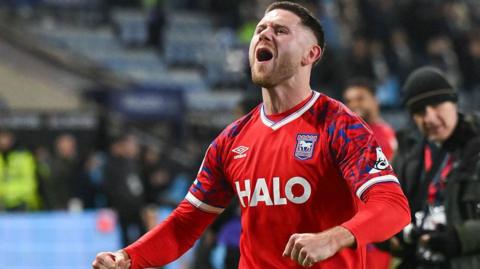 Wes Burns celebrates after a win with Ipswich. He wears the club's away colours.