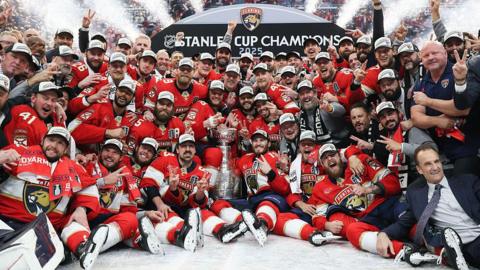 Florida Panthers players sit on the ice with the Stanley Cup
