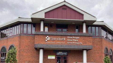 A building showing the Sandwell council logo and words including Sandwell. There are windows going across most of the visible section of the highest floor.