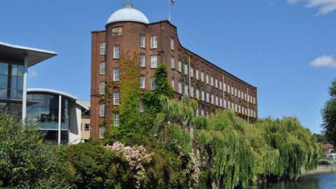 St James Mill - a five storey red brick mill with a dome on top located on the bank of the River Wensum