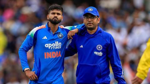 Shreyas Iyer (left) is helped from the field by a member of India's medical staff