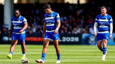 Beno Obano (left), Santiago Carreras (centre) and Ben Spencer (right) walk on the pitch looking dejected after the full-time whistle against Exeter