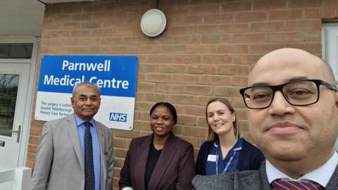 Mohsin Laliwala, a man wearing a grey suit, standing next to Mercy Oviasogie Advanced Nurse Practitioner, a woman in a purple blazer, Lauren Collins Practice Nurse wearing a blue dress and Nabeel Laliwala, a man with glasses.