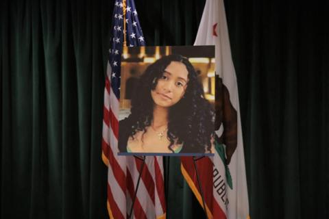 A photo of Celeste Rivas Hernandez is displayed on an easel in front of the US and California flags onstage at a media conference announcing charges against US singer David Anthony Burke, who is known professionally as D4vd.