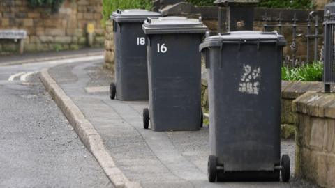 Three black bins on pavements outside homes