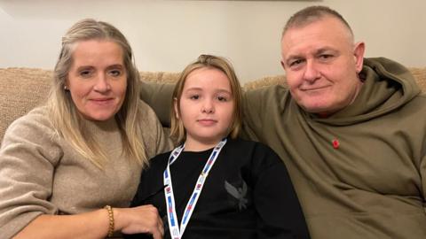 A woman on the left, a child in the middle and a man on the right. 