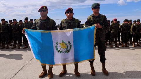 Guatemalan soldiers hold their national flag as they arrive in Haiti for a security mission, at Toussaint Louverture International Airport in Port-au-Prince