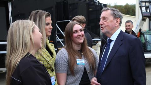 David Blunkett wearing a blue suit and tie meeting with three woman. All three women are looking at him as he talks to them