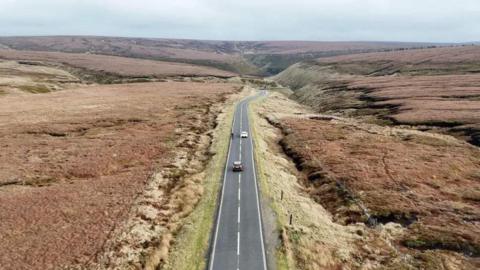 A near empty stretch of road runs between vast open countryside