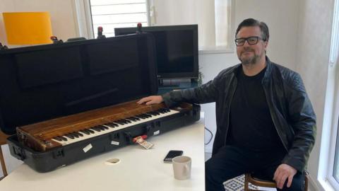 A man sat next to an old keyboard.