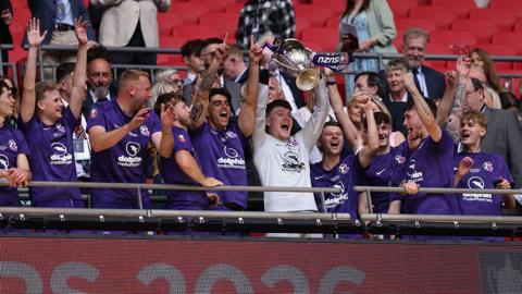 Callum Lee of AFC Stoneham lifts the Isuzu FA Vase trophy with teammates after winning the Isuzu FA Vase Final between AFC Stoneham and Cockfosters as part of Non-League Finals Day at Wembley Stadium on May 17, 2026 in London, England.