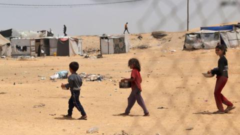 File photo showing displaced Palestinian children carrying containers with food in Rafah, in the southern Gaza Strip (19 May 2024)