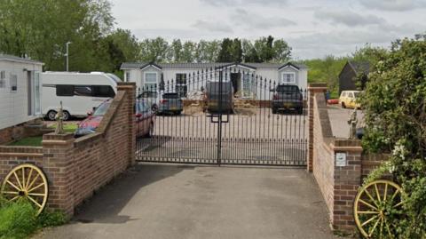 The outside of a Gypsy and Traveller site on St Ives Road in the village of Somersham. The front of the site has a black gated entrance. 