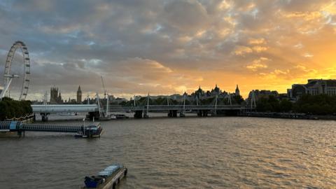 River Thames at sunset shows boats and the London skyline including London Eye and Big Ben