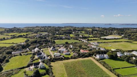 Sark from the air, showing a small group of houses centrally, with green fields surrounding them. 