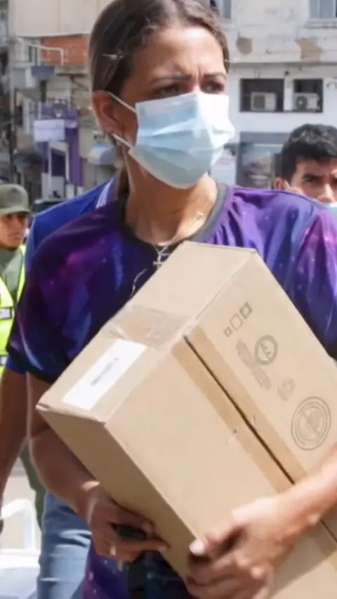 A person in a face mask carrying a box