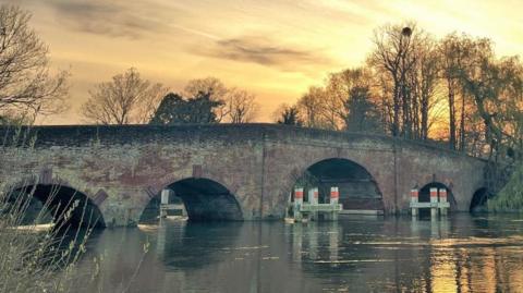 Brick bridge with multiple arches over the River Thames - view of the bridge is from the river bank.