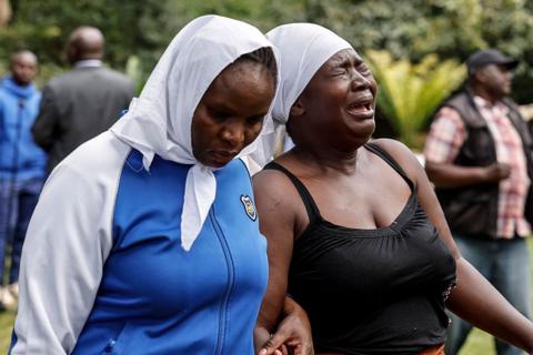 Two women wearing white headscarves mourning