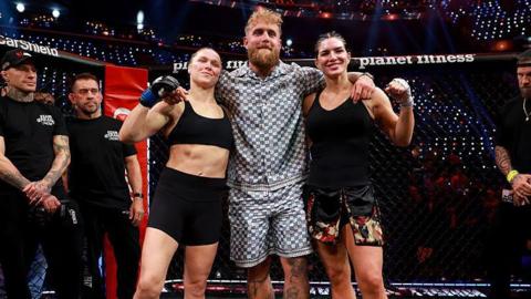 Jake Paul stands in between Ronda Rousey and Gina Carano