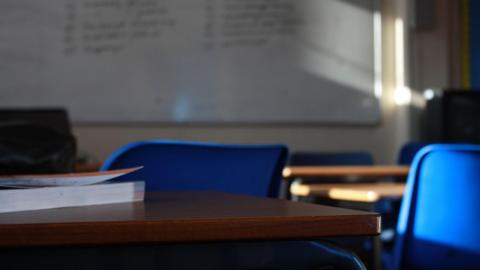 A classroom with a whiteboard, desks and blue chairs