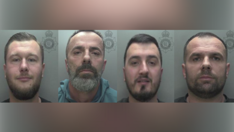 Police custody shots of Patryk Gilwanowski, Gazmir Hameti, Armir Metaj and Endri Arifaj (left to right). Patryk Gilwanowski is wearing a black top and has short, combed, brown hair and facial hair. Gazmir Hameti is wearing a blue hoodie and has short brown hair and greying facial hair. Armir Metaj is wearing a black T-shirt and has short black hair and black facial hair. Endri Arifaj is wearing a black top and has brown hair and facial hair. They are all stood in front of a grey wall.