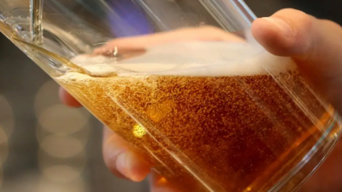A close-up of a golden fizzing beer being poured