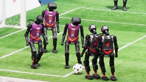 A group of robots playing football on a pitch.