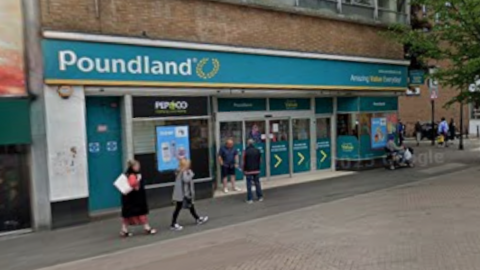 A Poundland store on a pedestrian street, with people walking in front of it. The store features the brand's turquoise logo with white writing and yellow garland.