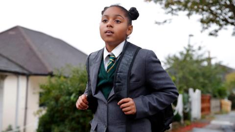 Girl aged 10 walking on residential street, wearing blazer