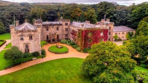 Aerial shot of Towneley Hall in Towneley Park, Burnley surrounded by trees.