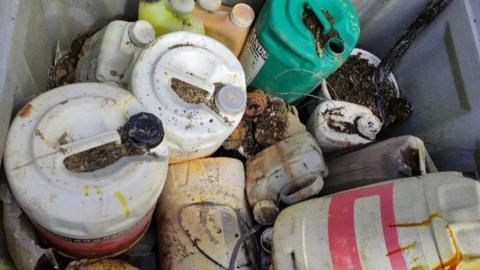 A selection of old containers used to store pesticides. They are all plastic and come in various colours, shapes and sizes. There are 13 in total. All of them look old and worn.