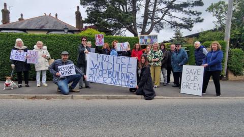 A number of residents in a residential street in Carleton holding signs up opposing the plans for new homes.