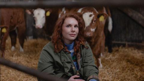 Joanne Coates photographer pictured in front of a group of cows 