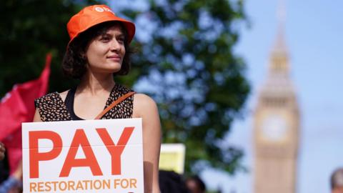 Junior doctor holding a sign that reads: 'pay restoration for doctors' during strike action in London