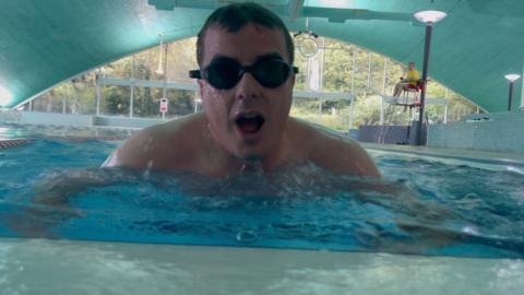 A man in a swimming pool wearing black goggles.