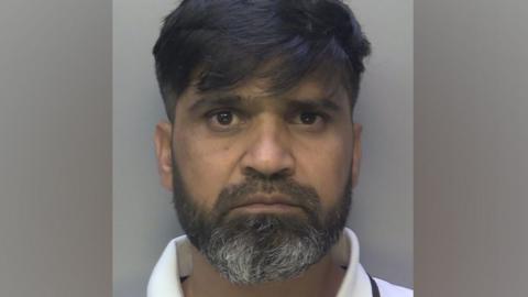 Police mugshot of Urfan Sharif. He has a beard and is looking straight at the camera.