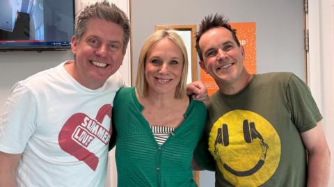 Dick and Dom, either side of Kirsten O'Brien, huddle together for a picture in the radio studio.