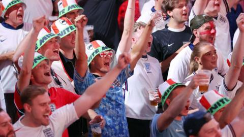 England fans celebrate, with their fists clenched in the air, as the team beats Mexico in the World Cup