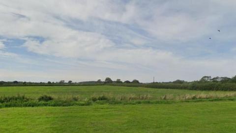 Greenfield land off Oak Road, with grass and shrubs in the image
