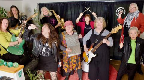 The band performing. Lisa is holding her microphone aloft as she belts out a song.