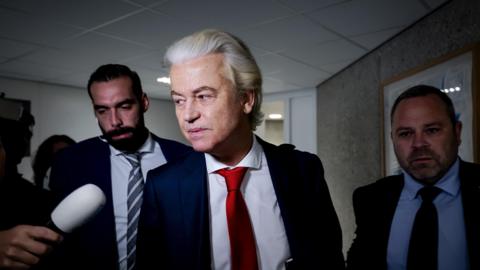 Geert Wilders wearing a white shirt, red tie and blue suit jacket