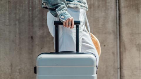 Cropped shot of young woman with suitcase walking