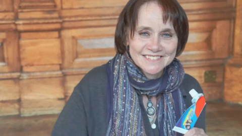 Councillor Zoe Cookson, pictured with short brown hair holds up a used toothpaste tube.