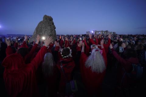 People gather so see the sun rise over Stonehenge