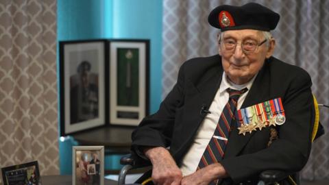 Jim Wren sits in his living room wearing his uniform and multiple decorations on his chest