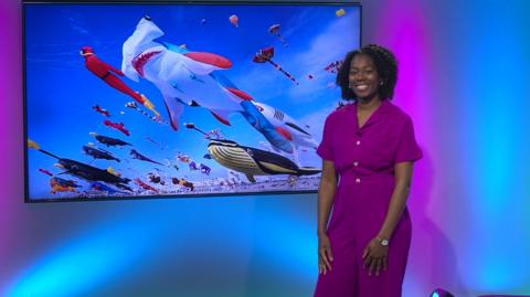 Shanequa in the Newsround studio with kites in the screen