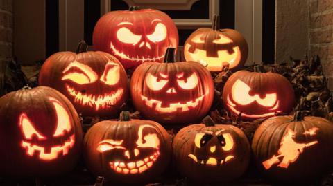 A stack of carved pumpkins with illumination inside