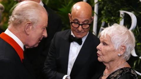 The King speaks to Dame Judi Dench, while Stanley Tucci looks on, at Windsor Castle