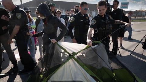Police remove tents which demonstrators were using to block a vehicle entrance to an ICE facility outside Chicago