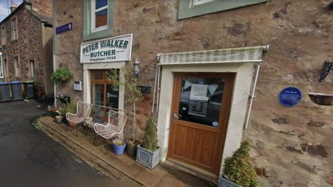 The front door of a butchers in Coldingham with a couple of chairs outside